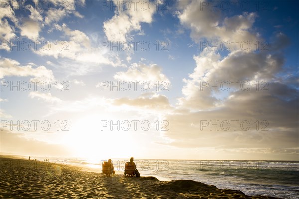 People relaxing on beach at sunrise