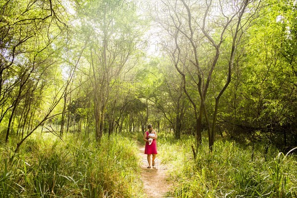 Caucasian woman carrying baby in lush jungle