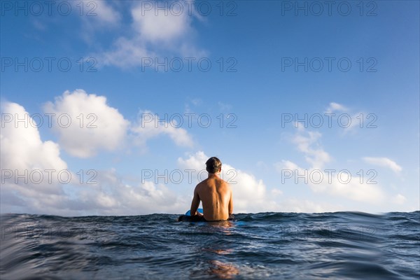 Surfer sitting on surfboard in ocean