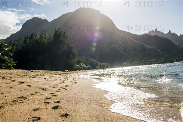 Footprints on sand near waves on tropical beach