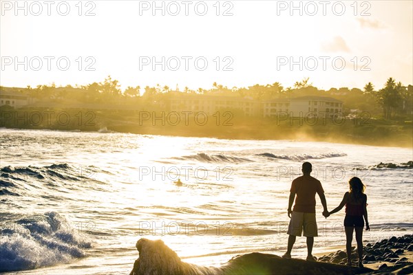 Couple holding hands near ocean on beach