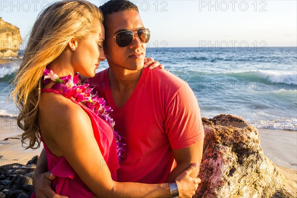 Couple hugging near rock formation on beach