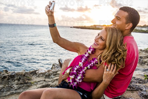 Couple taking cell phone photograph on beach
