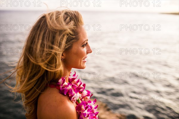 Caucasian woman wearing flower lei by ocean