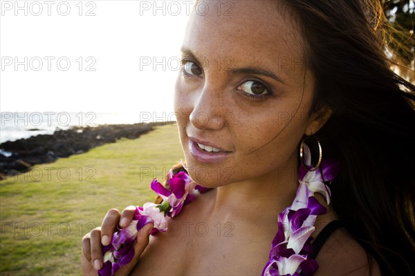 Caucasian woman wearing flower lei near ocean