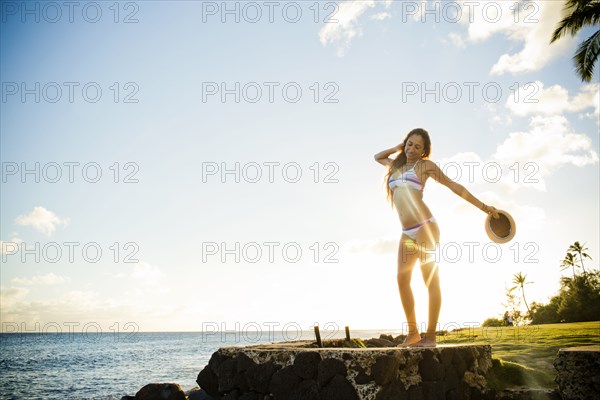 Woman standing on wall near ocean