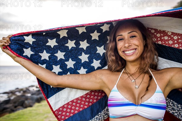 Woman standing under American flag quilt