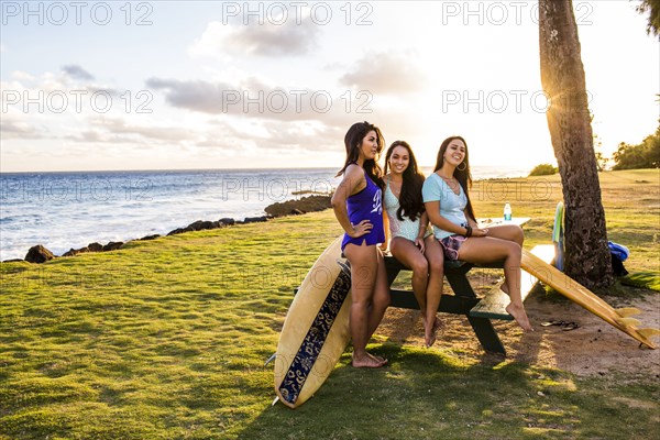 Pacific Islander women smiling on picnic table near beach