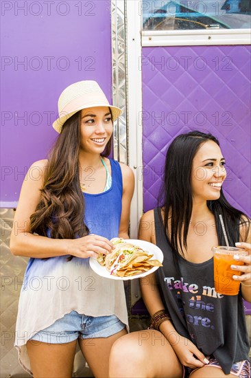 Pacific Islander women eating and drinking near food cart