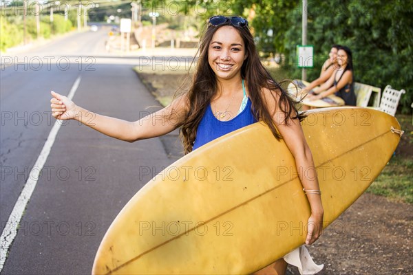 Pacific Islander surfer hitch hiking on rural road