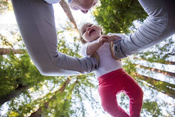 Low angle view of Caucasian mother playing with baby under trees