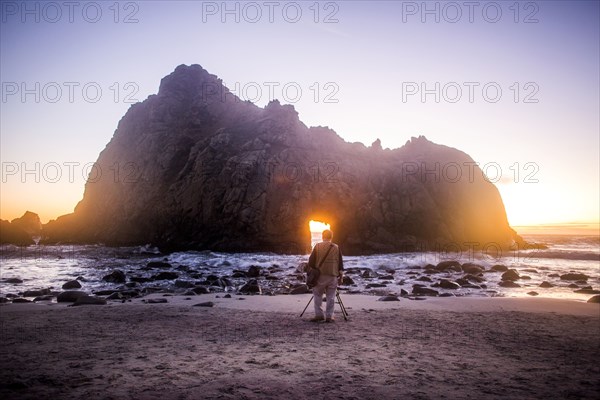 Photographer photographing rock formation on beach