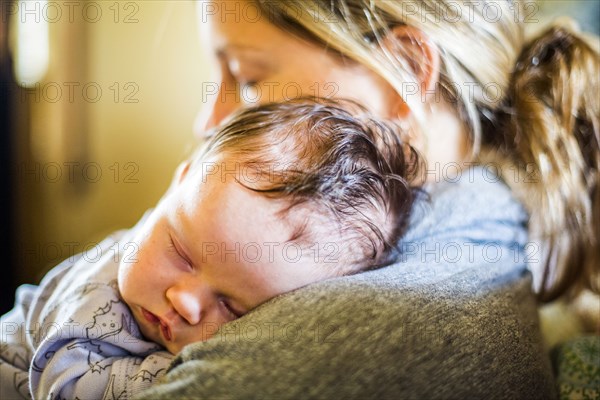 Caucasian mother holding sleeping baby son