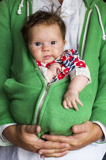 Caucasian father holding baby girl in zipped hoodie