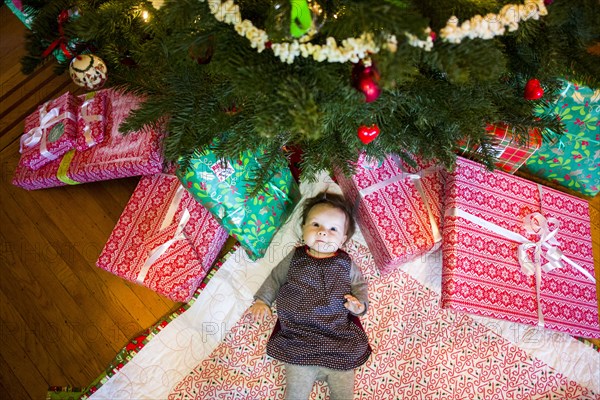 High angle view of Caucasian baby girl laying under Christmas tree