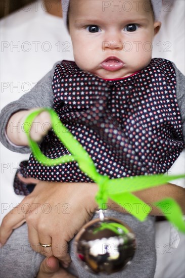 Close up of Caucasian baby girl holding Christmas ornament