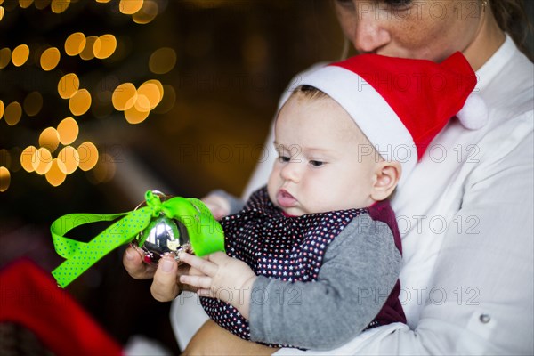 Close up of mother holding baby girl with Christmas ornament