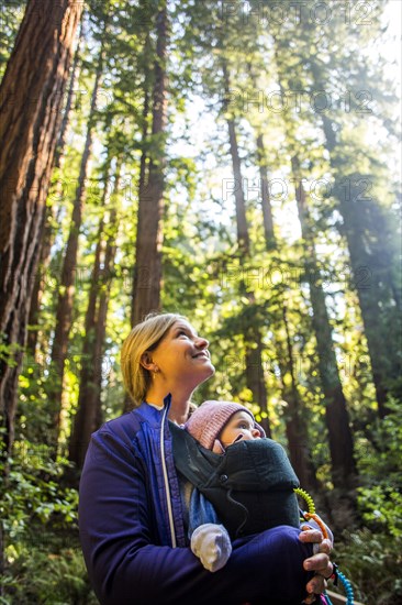 Low angle view of Caucasian mother carrying daughter in forest