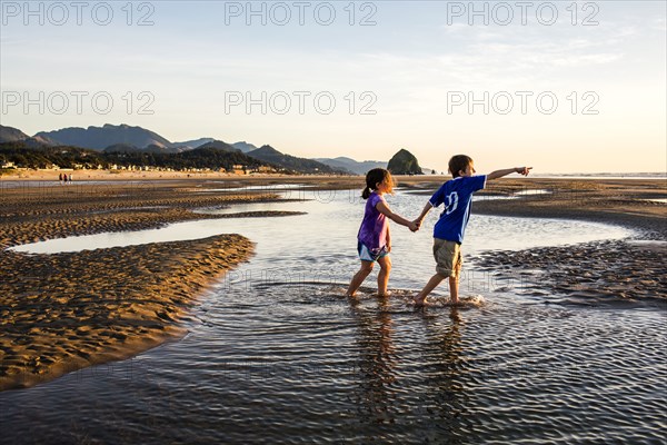 Caucasian children walking in tide pools on beach