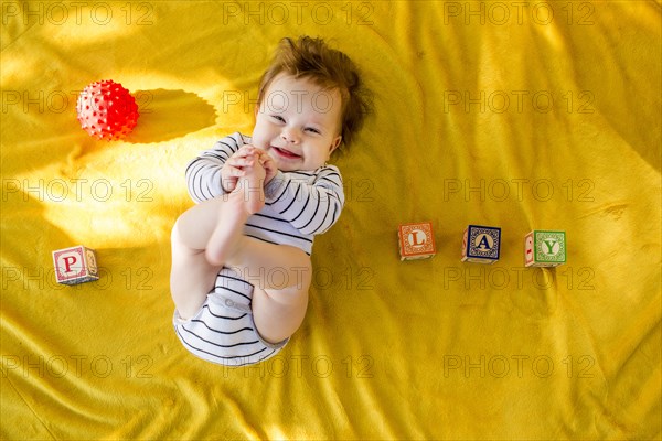 Caucasian baby girl playing with blocks on bed