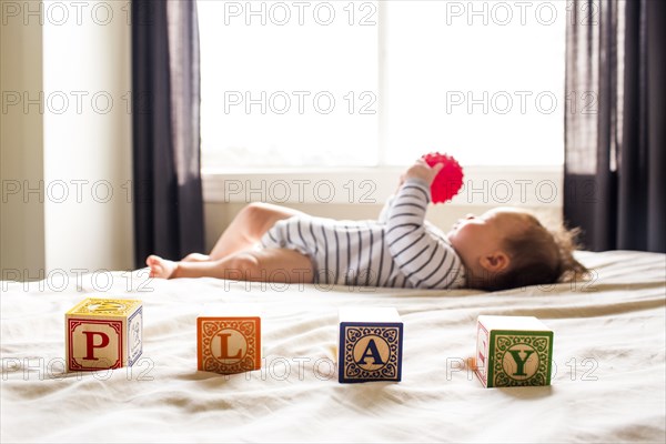 Caucasian baby girl playing on bed