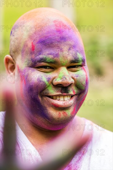 Smiling man covered in pigment powder gesturing peace sign