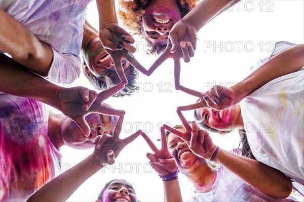 Low angle view of friends covered in pigment powder making star shape