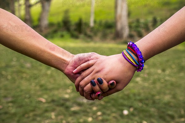 Close up of women holding hands in park