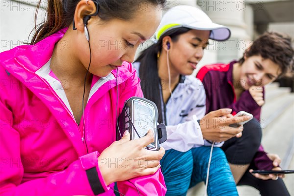 Runners using cell phones and earbud on city sidewalk