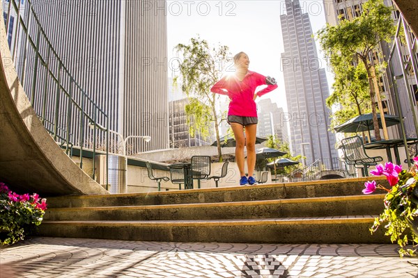 Runner standing on city steps near high rise buildings