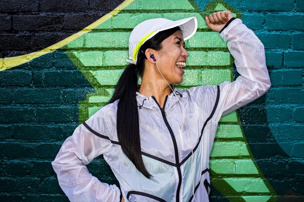 Asian runner standing near graffiti wall