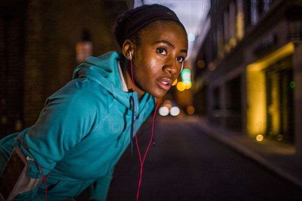 Black runner resting on city street at night