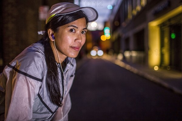 Asian runner resting on city street at night