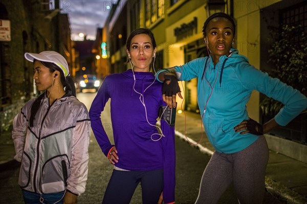 Runners standing on city street at night