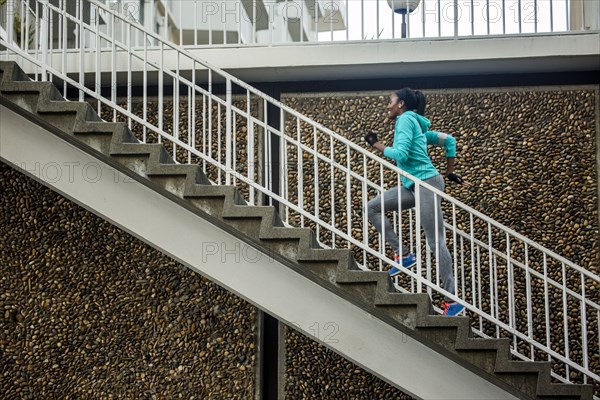 Black runner climbing staircase