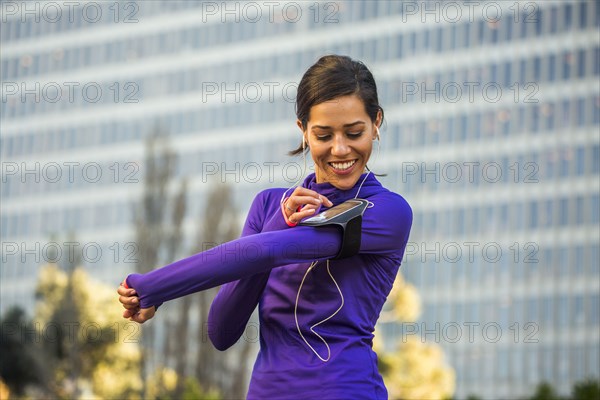 Hispanic runner using cell phone near high rise building