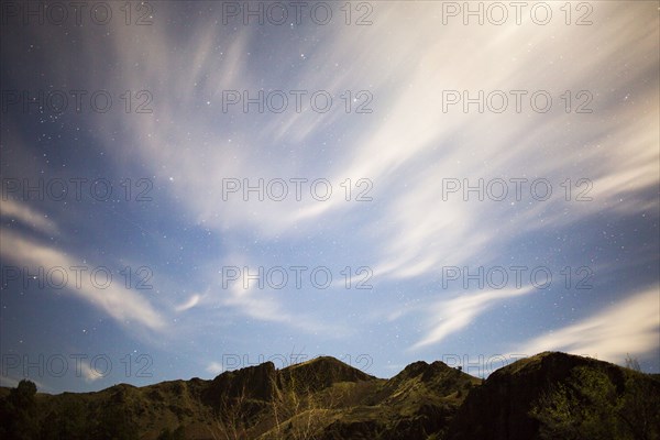 Low angle view of hilltops under cloudy sky