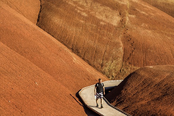 Caucasian hiker on wooden walkway in desert hills