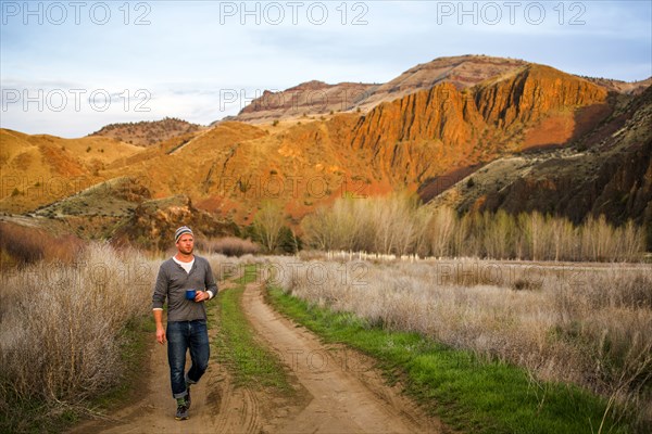 Caucasian man drinking coffee on dirt path