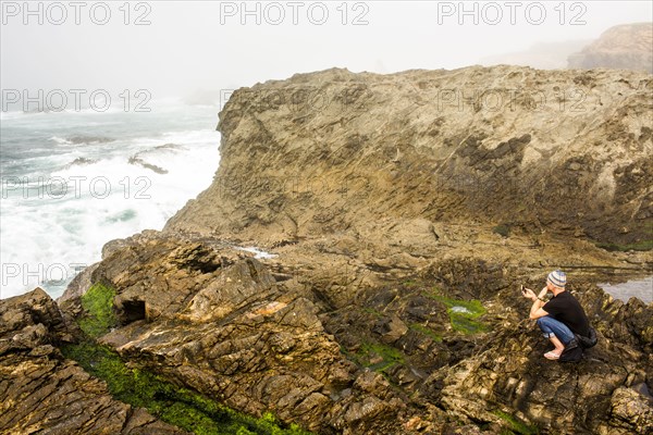 Caucasian hiker sitting on cliffs over ocean