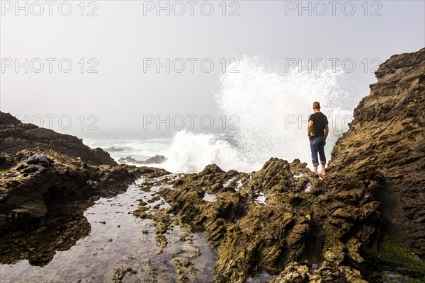 Caucasian hiker watching crashing ocean waves