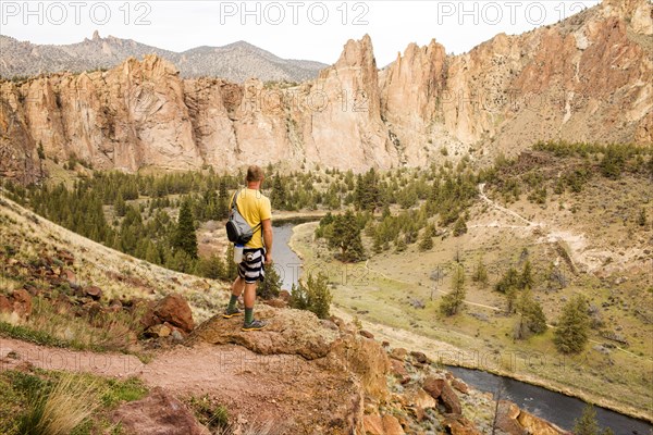 Caucasian hiker admiring hills and stream in desert landscape