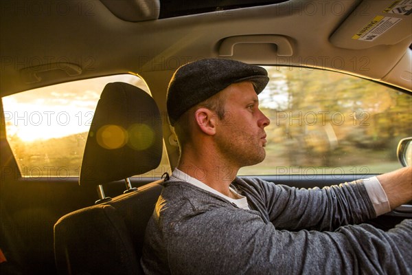 Caucasian man driving car at sunset