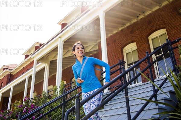 Hispanic woman carrying yoga mat on staircase