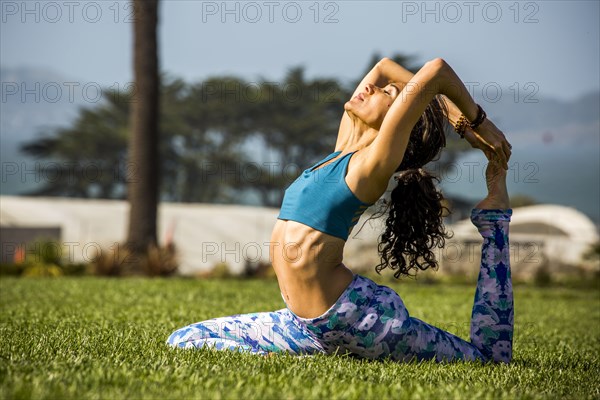 Hispanic woman practicing yoga in park