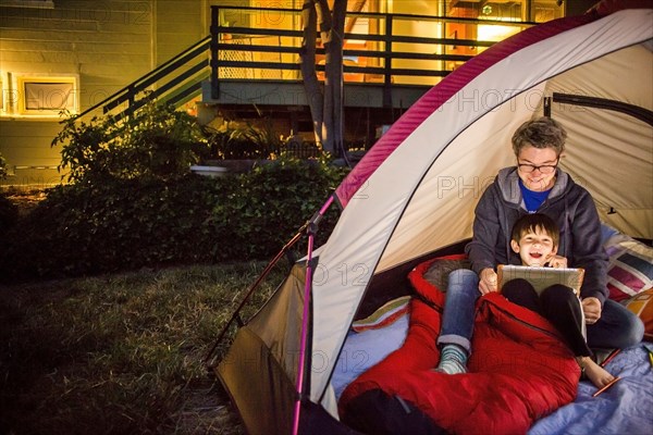 Mother and son using digital tablet in backyard tent