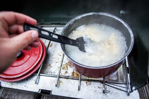 Hand stirring pot on campsite stove