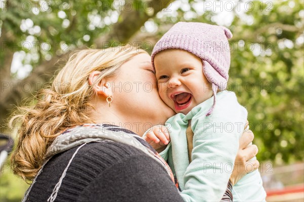 Caucasian mother kissing baby daughter outdoors