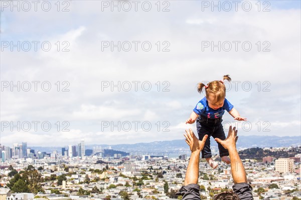 Caucasian father tossing daughter over San Francisco cityscape