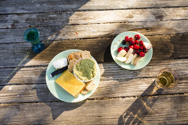 Plates of cheese and fruit on wooden table